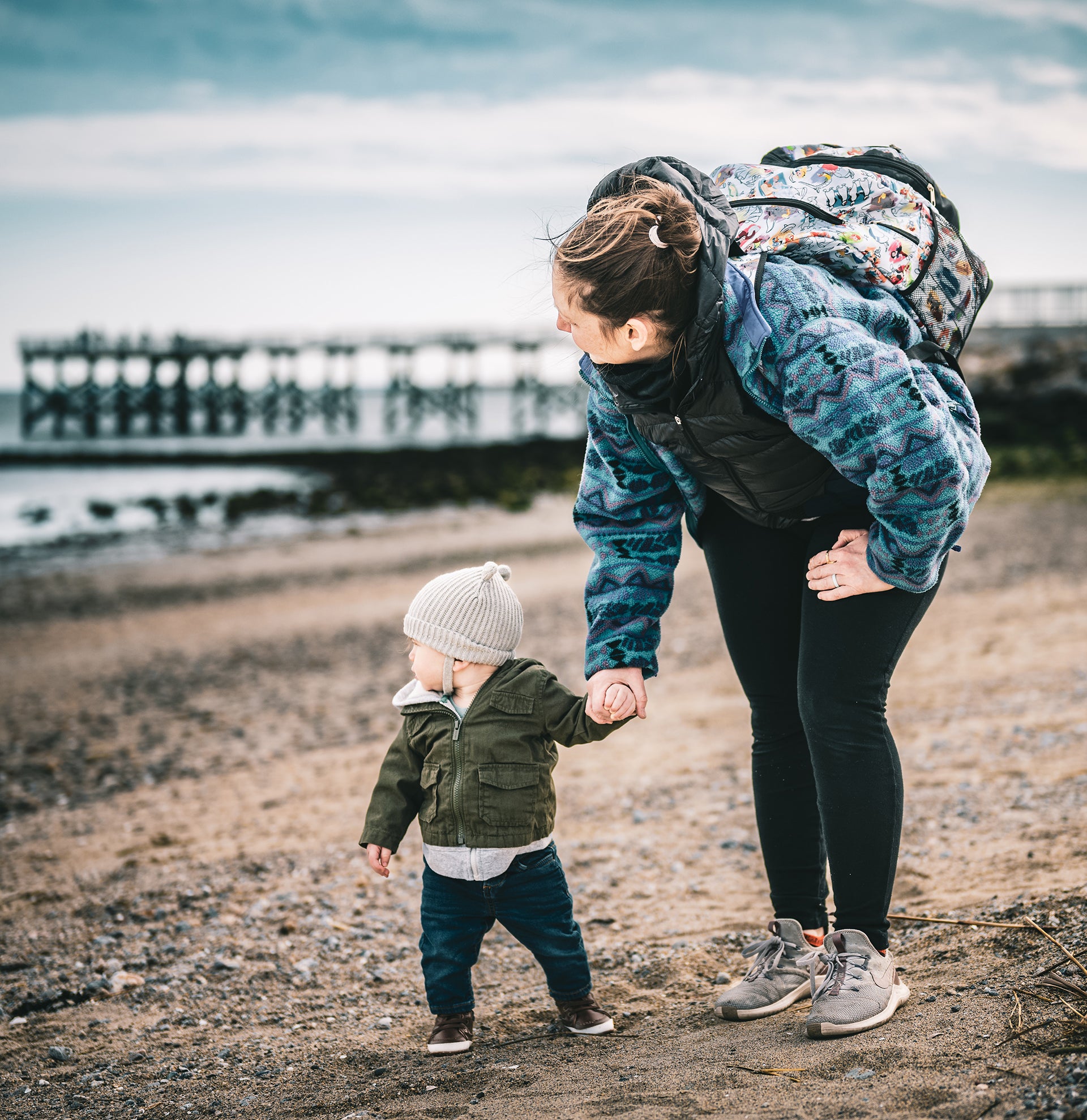 Mutter mit Kind am Strand blicken Richtung Wasser