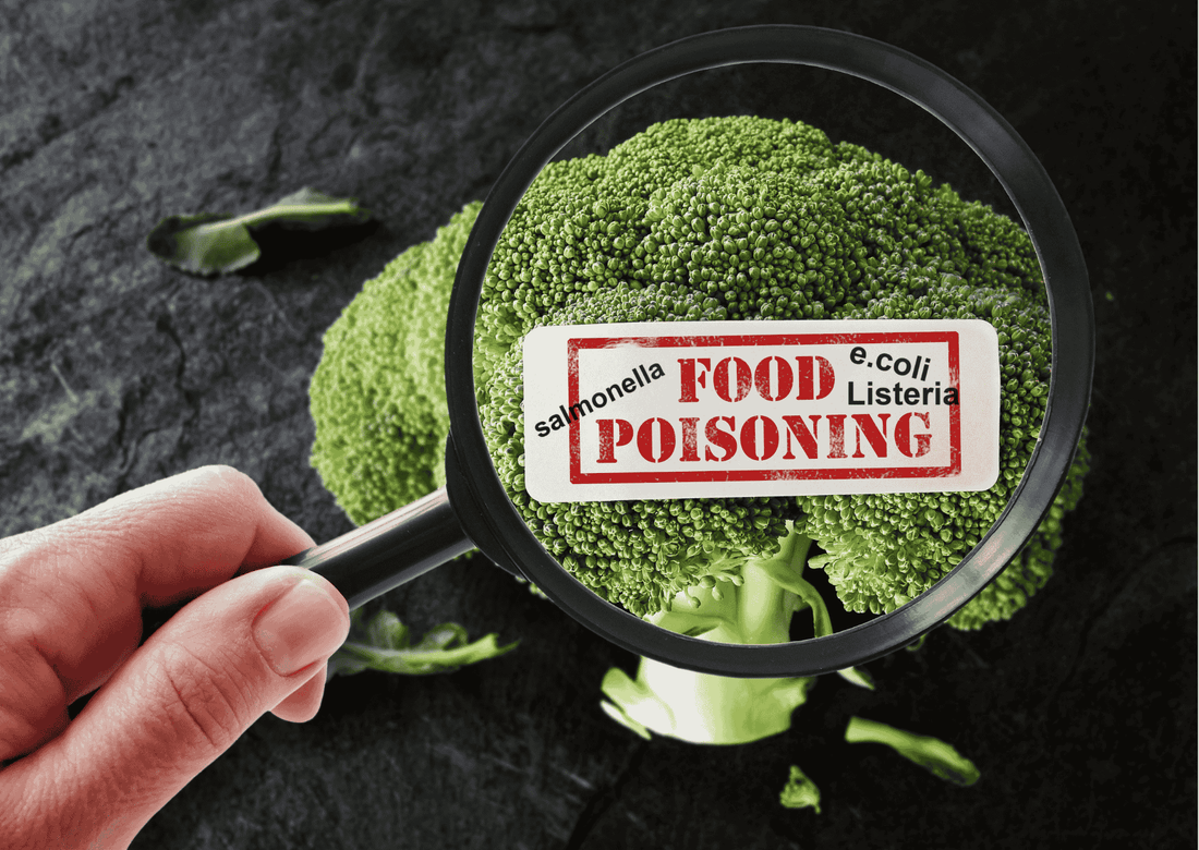 Lupe über frischem Brokkoli mit Warnschild „Food Poisoning“; Hinweis auf Salmonellen, E.coli und Listerien
