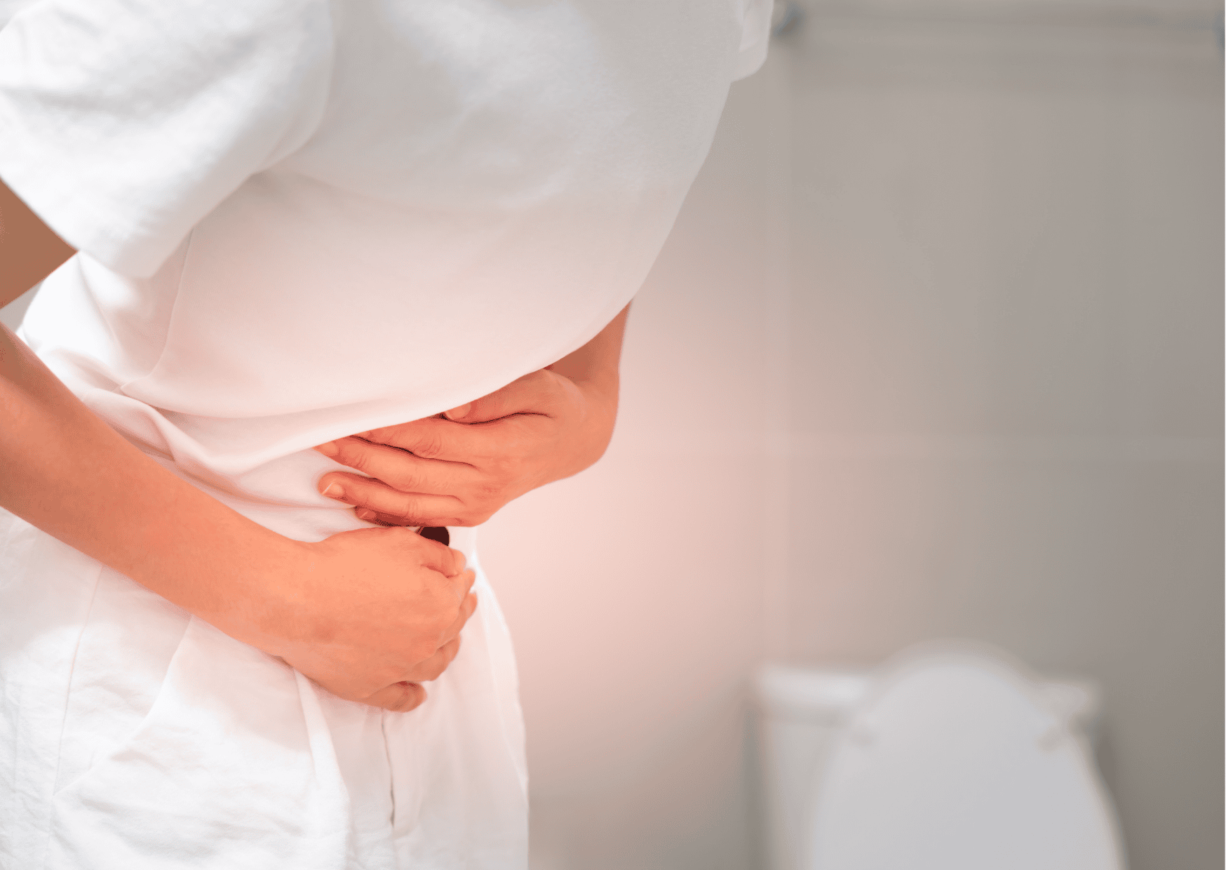 Frau hält sich den Bauch vor Schmerzen, Symbol für Verstopfung.