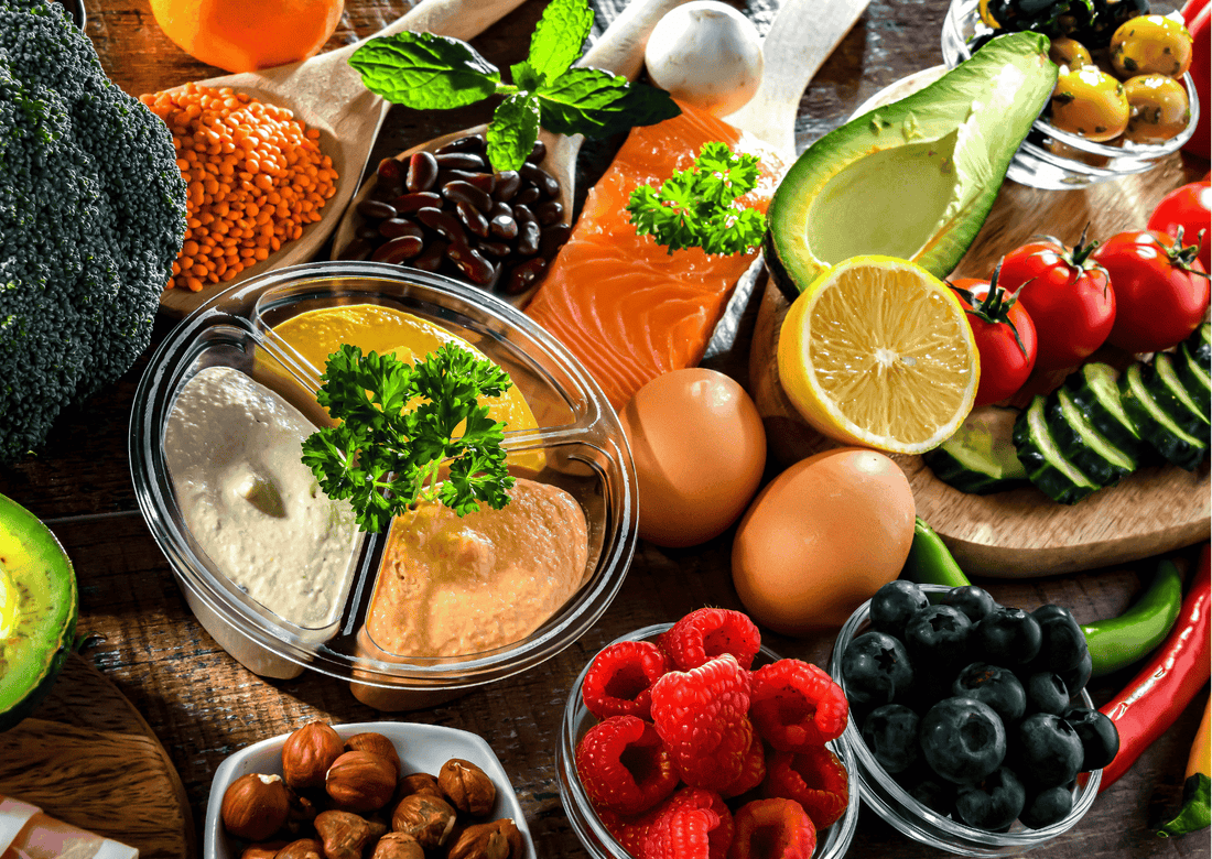 Auswahl gesunder Lebensmittel mit Fisch, Eiern, Avocado und Beeren auf Holztisch