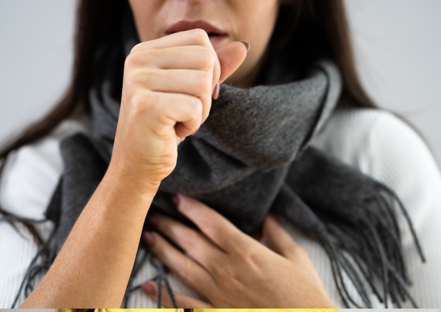 Frau mit einem dunklen Schal um den Hals, die sich die Hand vor den Mund hält und hustet