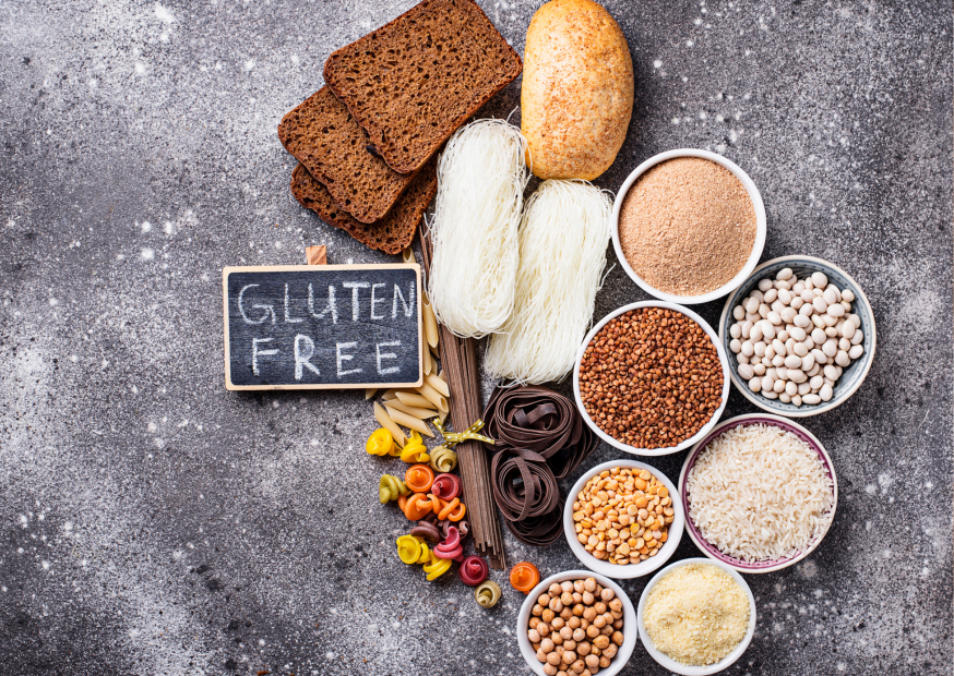 Brote, Gewürze und andere Lebensmittel liegen auf einer grauen Tischplatte. Daneben steht Gluten Free auf einem Schild
