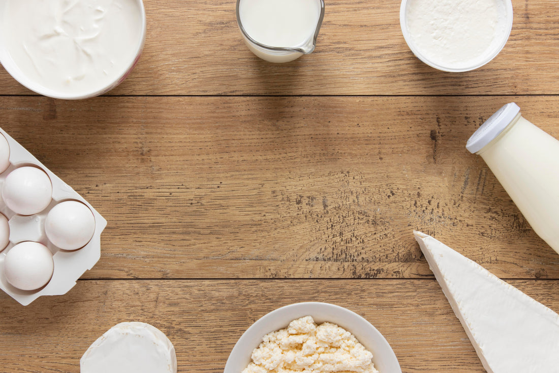 Milchprodukte wie Joghurt, Quark, Milch und Eier auf Holztisch angeordnet; Auswahl an Lebensmitteln mit Laktose