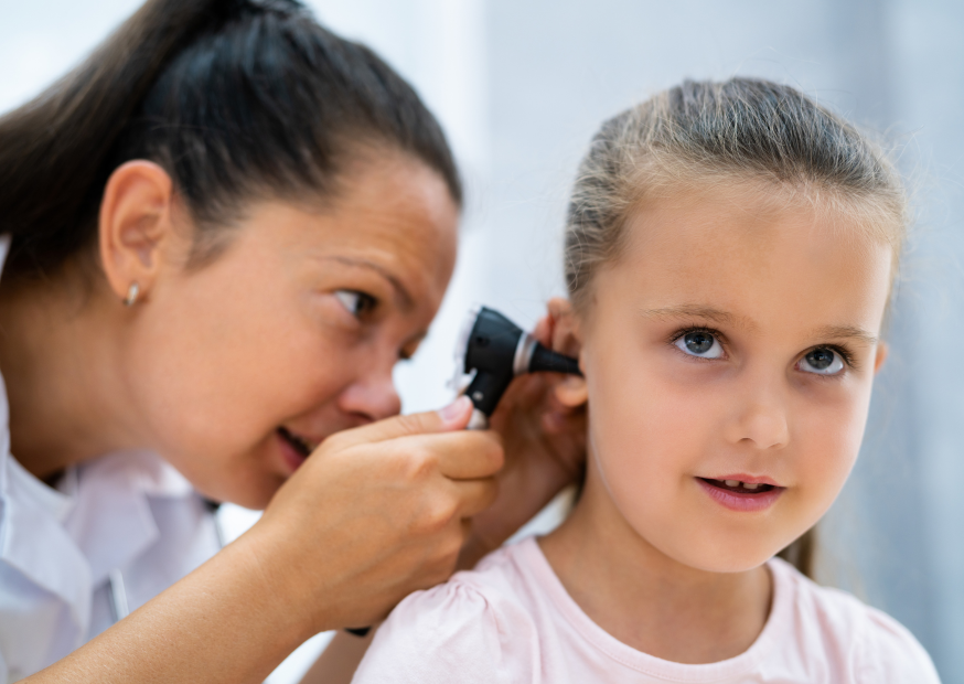 Kinderärztin schaut einem jungen Mädchen ins Ohr