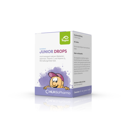 Produktbild schräge Ansicht von Lactobact JUNIOR DROPS 60 Drops mit lilafarbenem Aquarell Wasserfleck und Karikatur mit freundlichem Gesicht und rosa Cappy auf der Verpackung.