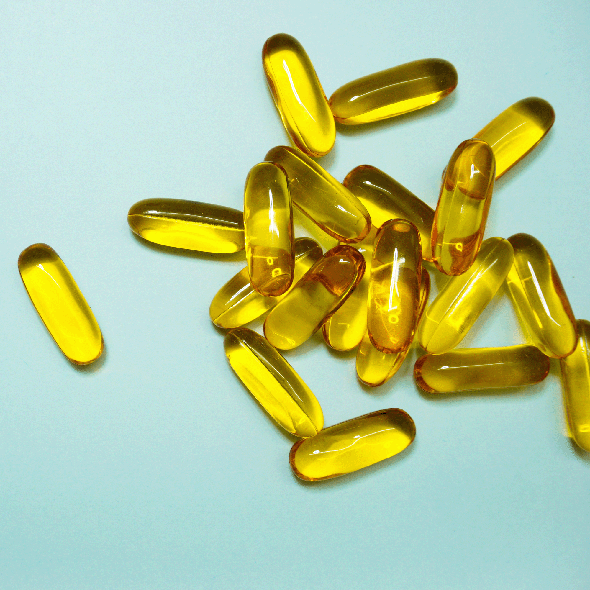 Mehrere Omega-3 Kapseln auf hellblauem Hintergrund von oben